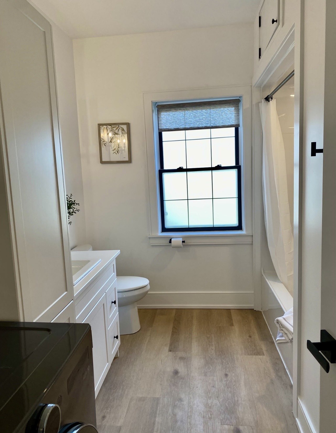 Bright bathroom with window, white vanity and wood-look floor